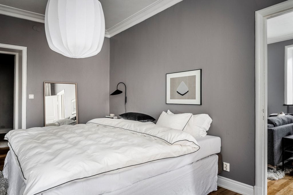 A bedroom with dark gray walls and white fabrics