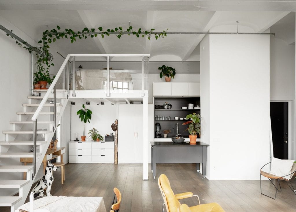 A kitchen with white cabinets, black countertops, black niche, stainless steel appliances, black kitchen island