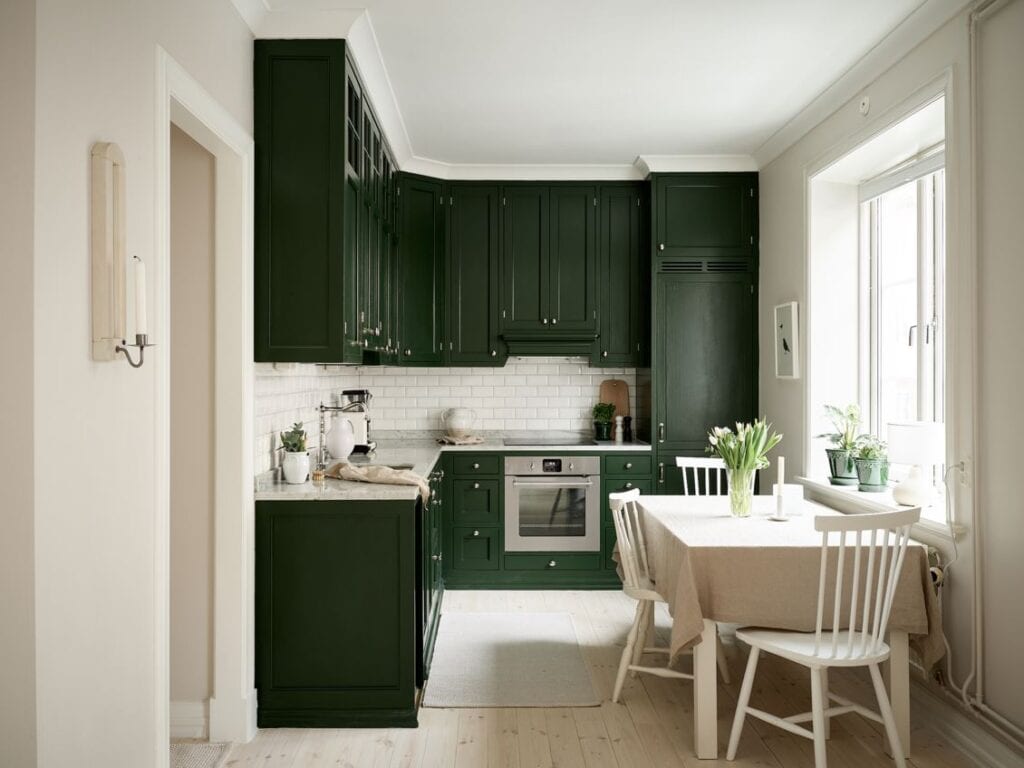 Forest green kitchen cabinets, white subway tile backsplash and white marble countertops