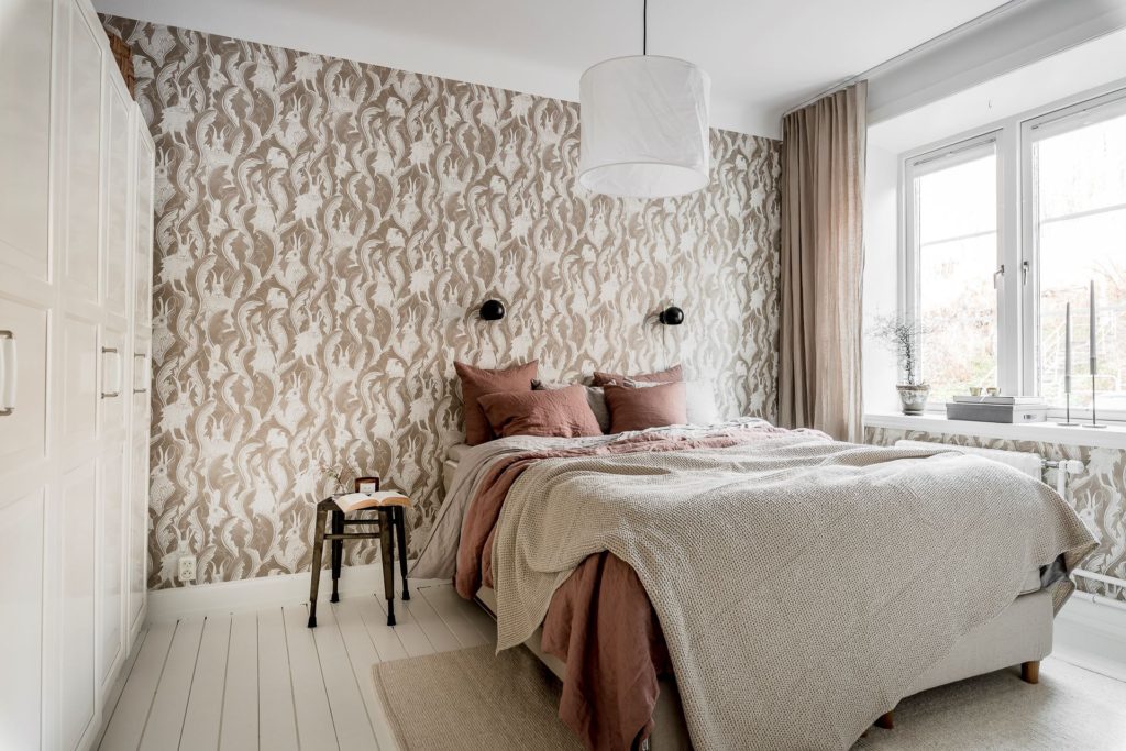 A bedroom wallpaper in brown tones complemented with terracotta textiles