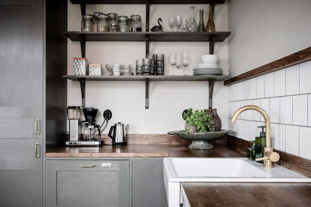 An olive green kitchen with wood countertops and open wall shelving