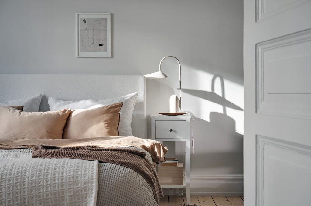 A light grey bedroom with warm textiles on the bed