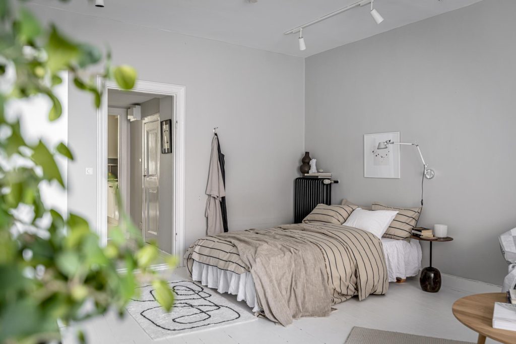A light grey studio apartment bedroom with beige striped bedding