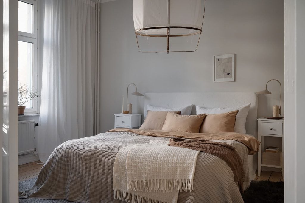 A light grey bedroom with warm textiles on the bed