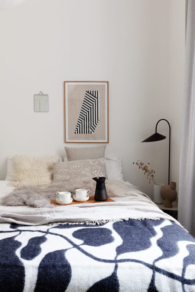 Black and white Linnea Andersson blanket in a white bedroom with a Ferm Living Arum floor lamp