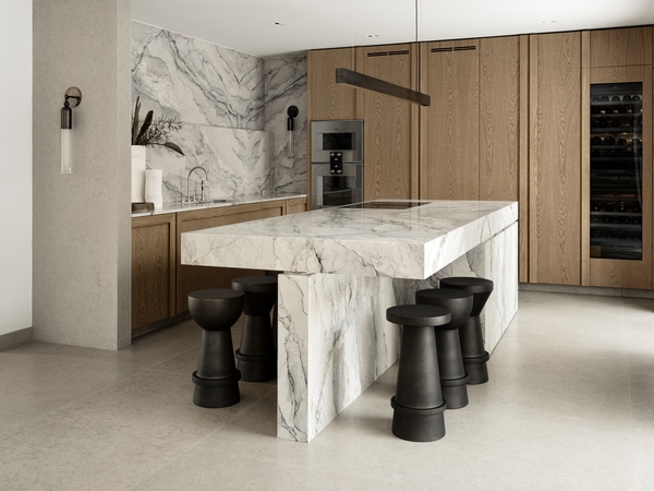 A tick marble kitchen island in a soft wood kitchen with eye-catching bar stools