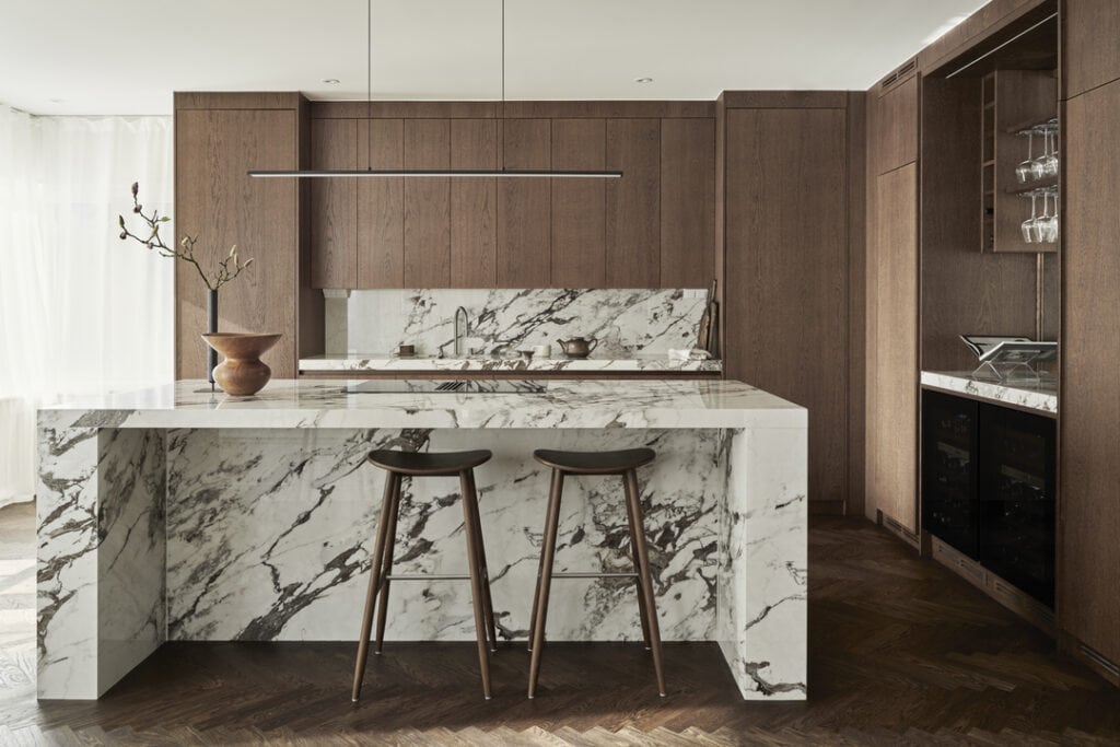 An impressive marble kitchen island in a kitchen with dark wood cabinets