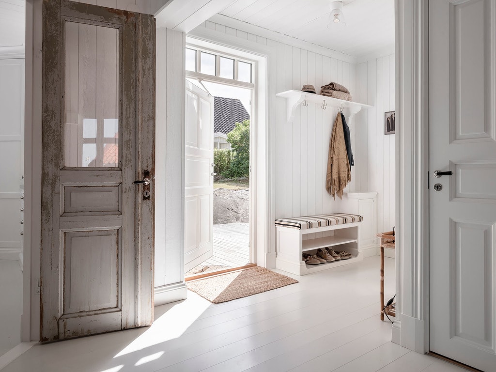 A white and beige mudroom bench against white shiplap walls