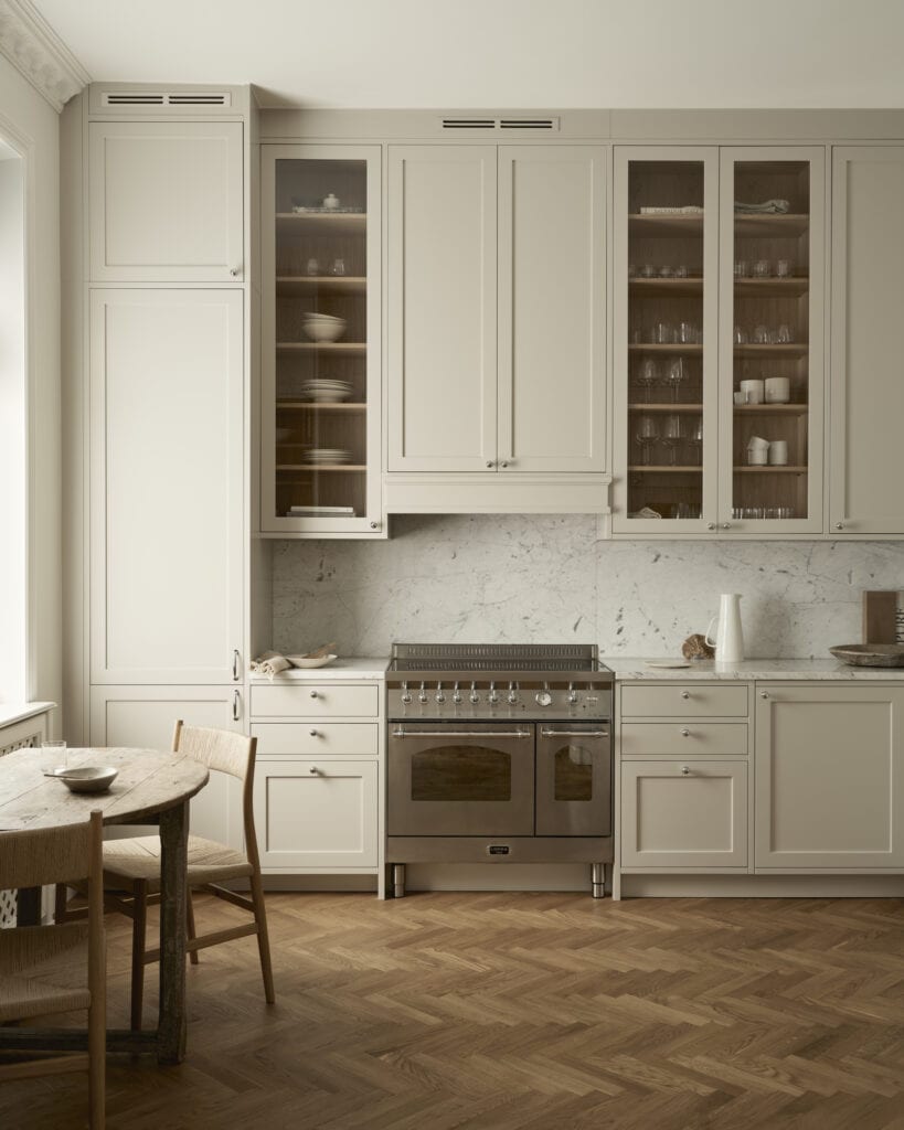 A floor to ceiling off-white shaker kitchen with glass cabinet doors