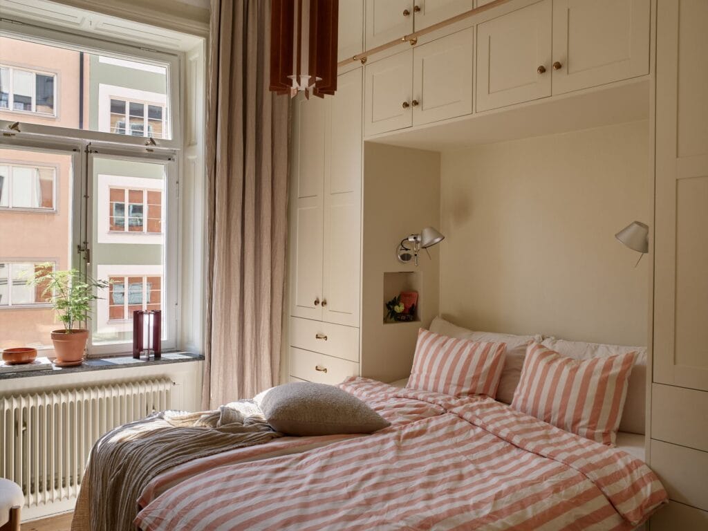 A beige bedroom with a custom-built wardrobe around the bed