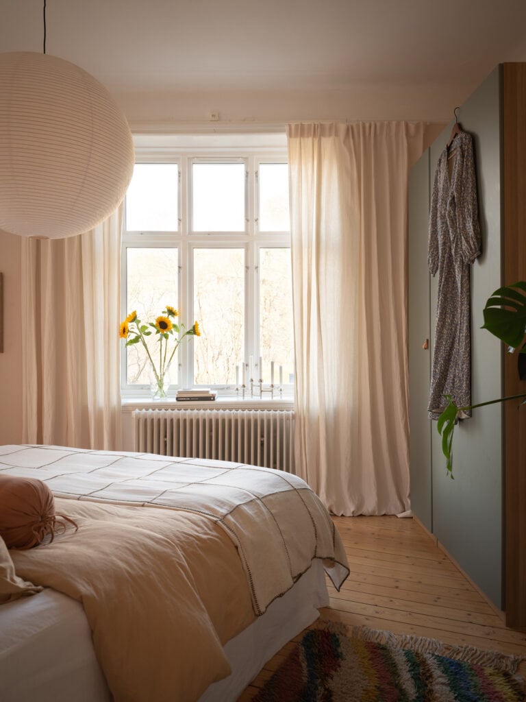 A bedroom with a light pastel pink wall color