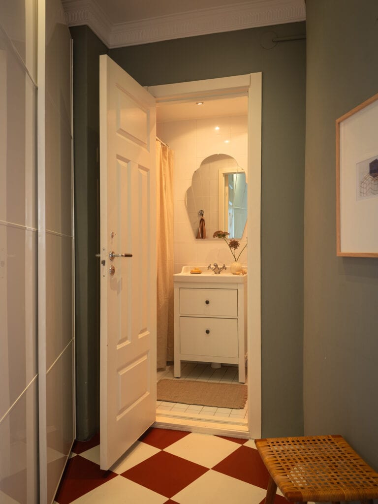 A white bathroom with a uniquely shaped mirror on the wall