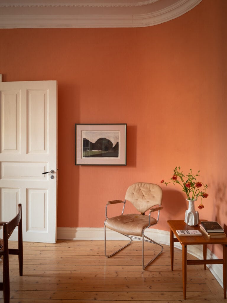 A living room with rich pink walls and vintage pieces
