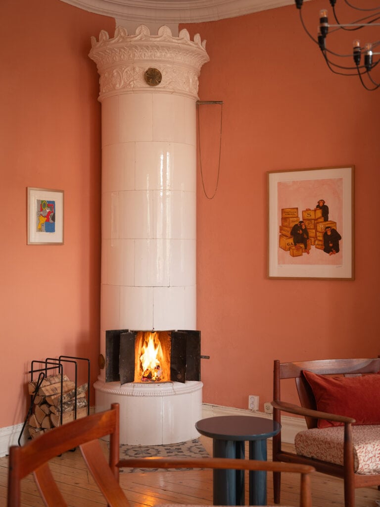 A living room with rich pink walls and a white fireplace