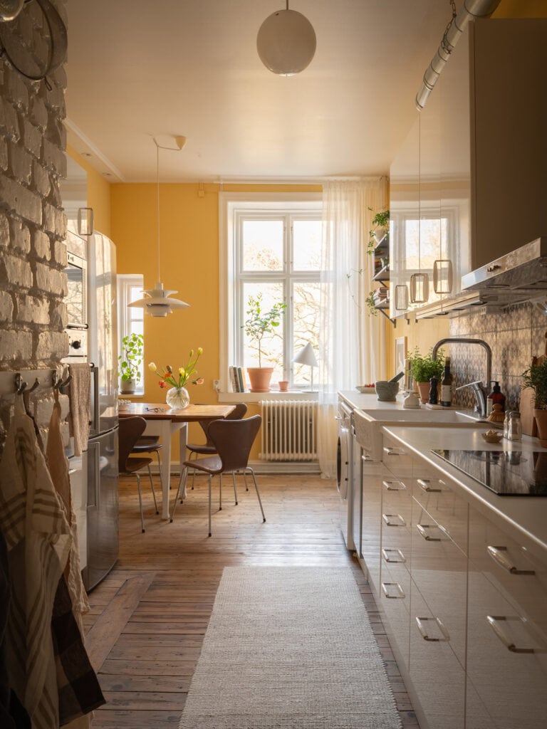 A basic white kitchen with a warm yellow wall color and a dining area with vintage leather chairs