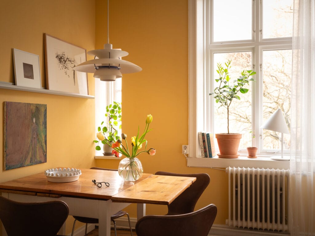 A basic white kitchen with a warm yellow wall color and a dining area with vintage leather chairs