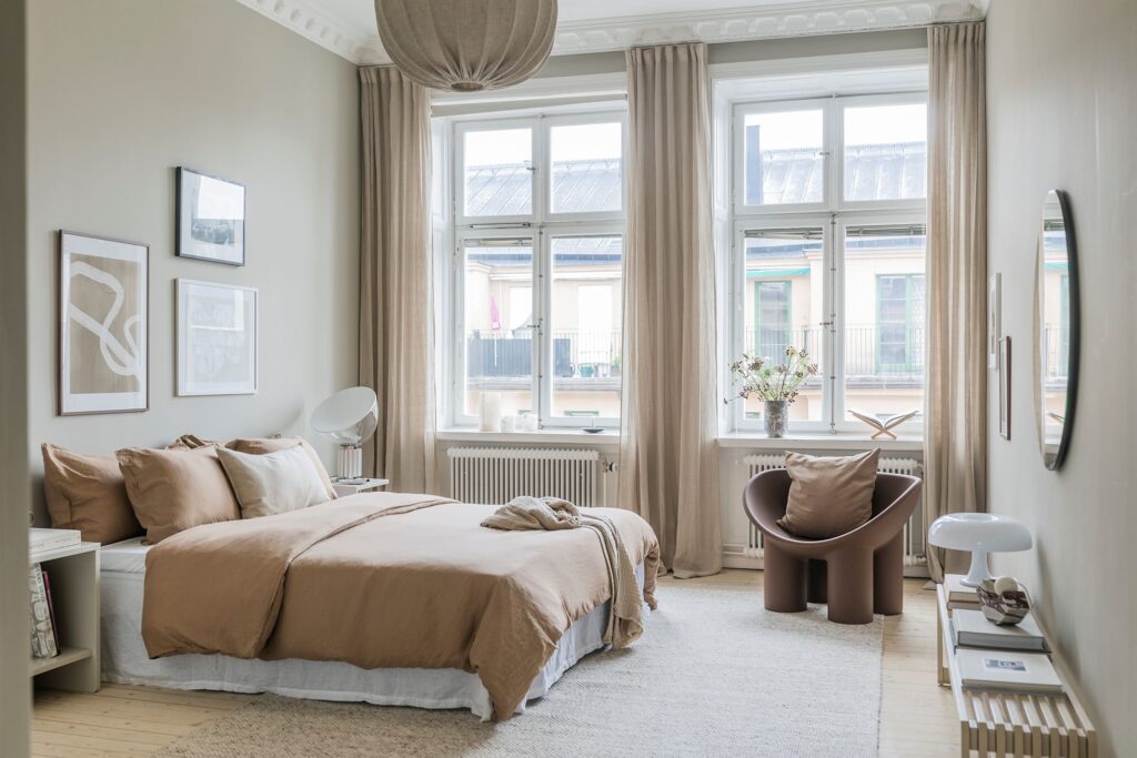 A beige bedroom with beige textiles and a beige gallery wall