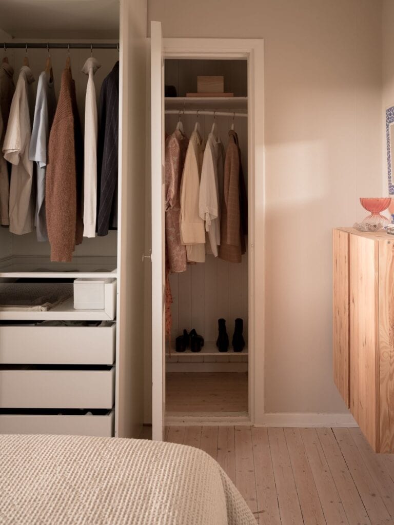 A bedroom with beige walls and a minimal decor, open wardrobe and walk-in closet