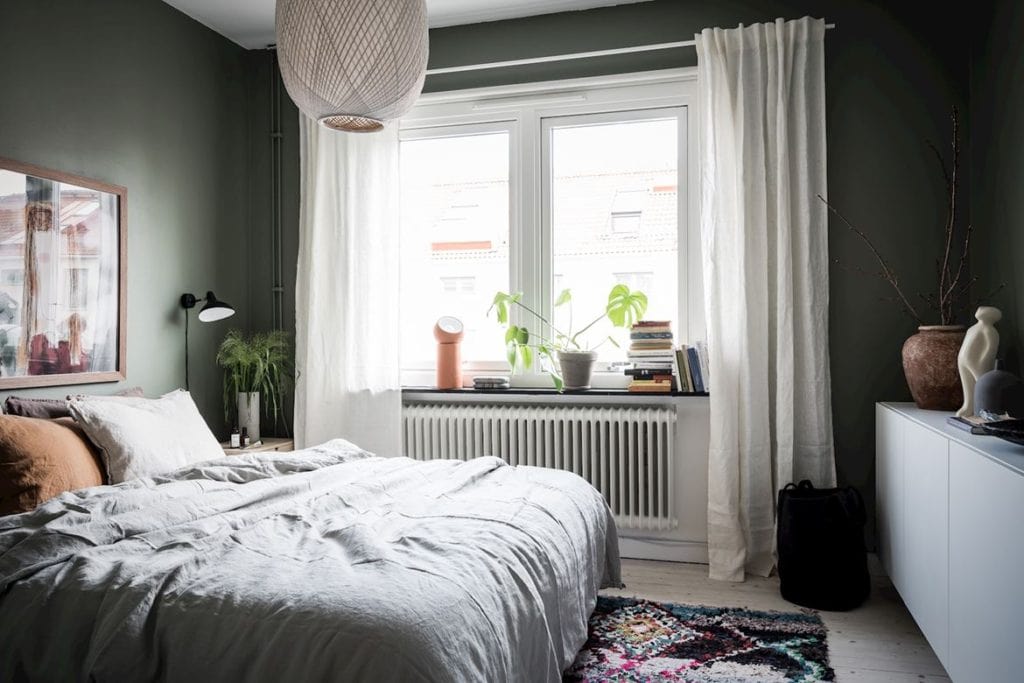 A deep green bedroom wall color and white furniture