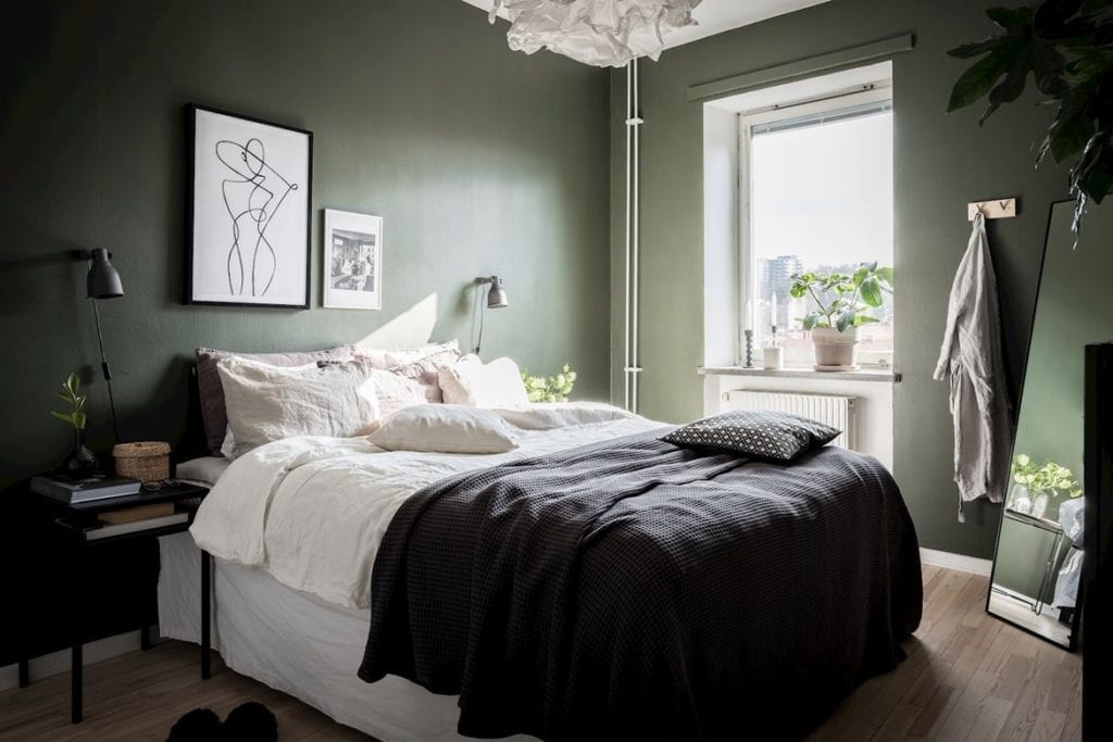 A deep green wall color in a bedroom with black and white details
