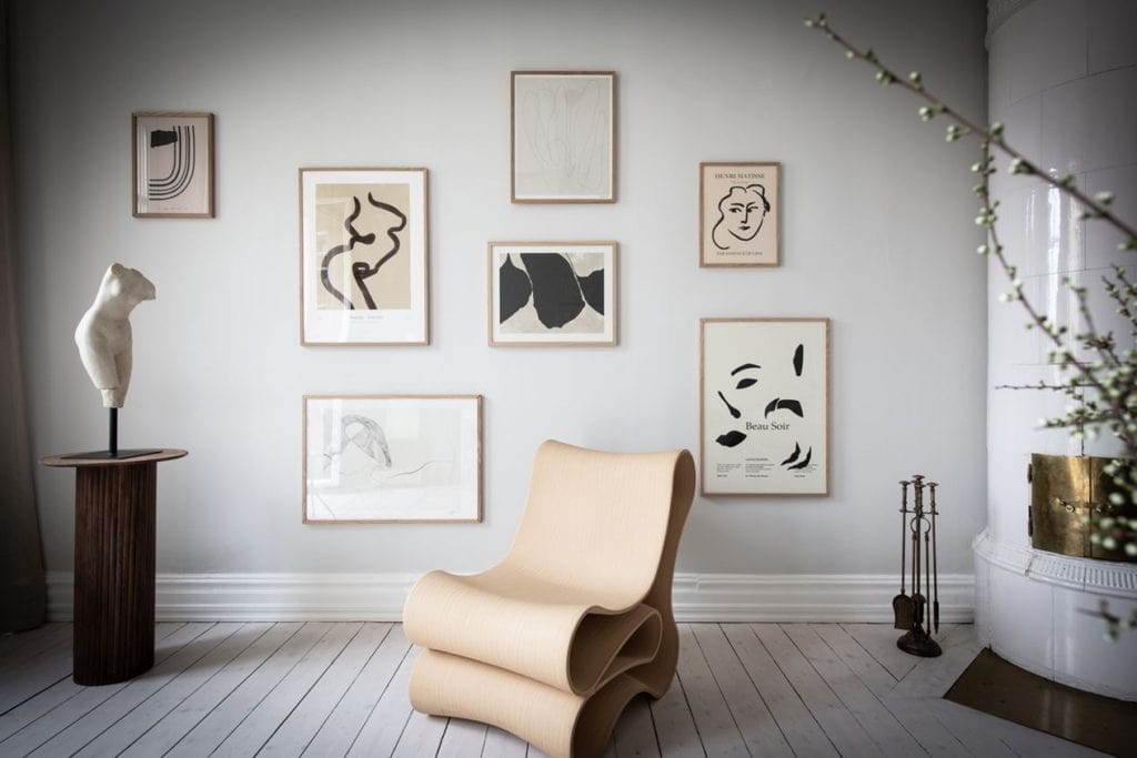 A gallery wall in neutral colors and oak frames on a light grey living room wall