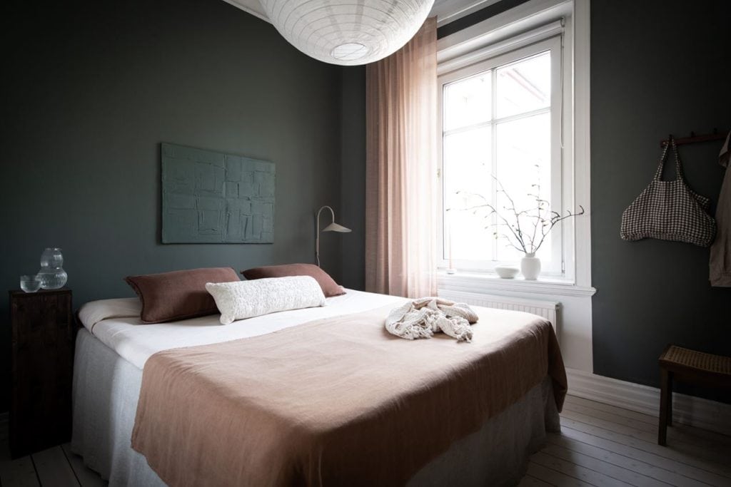 A dark green bedroom with beige textiles