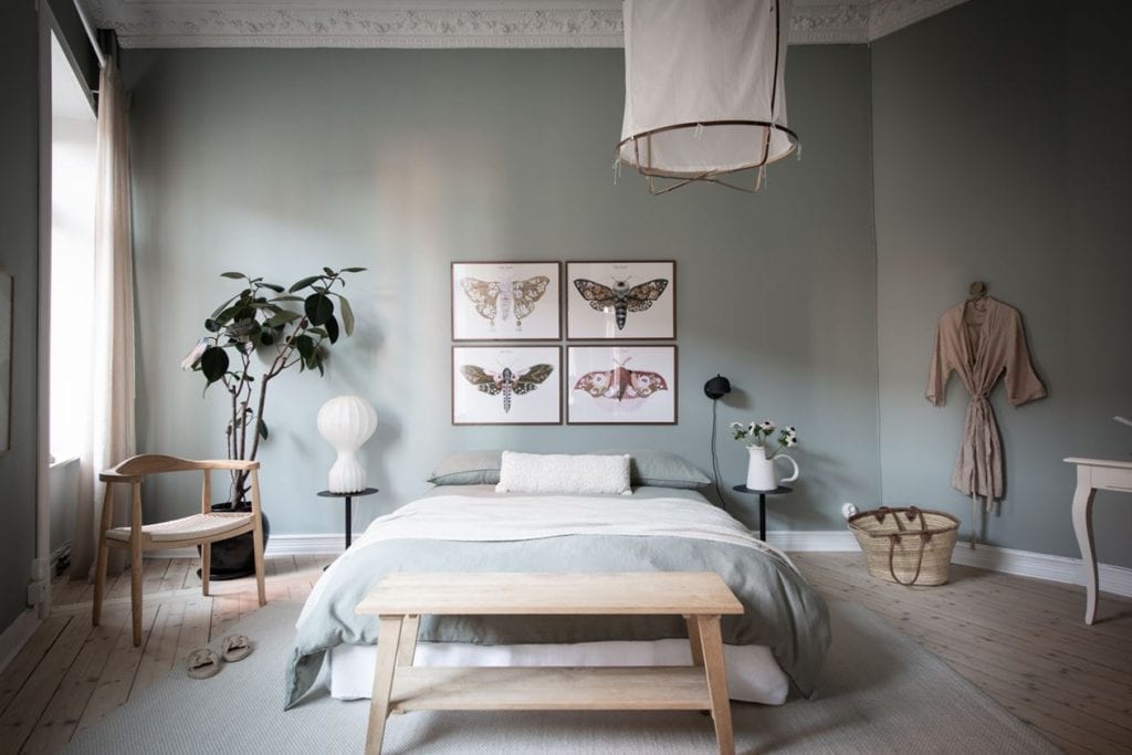 A sage green bedroom with a symmetrical gallery wall above the bed