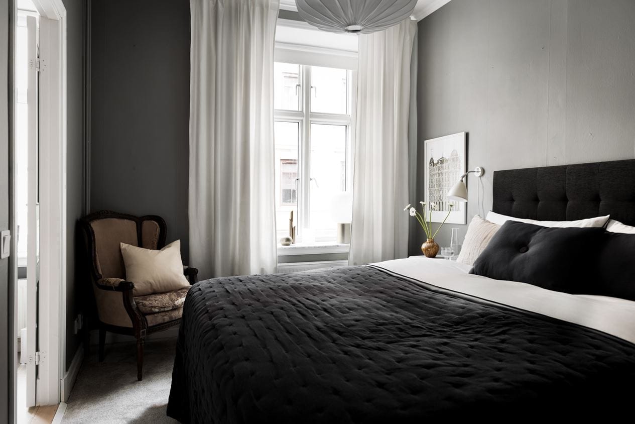 A grey bedroom paired up with a black headboard and comforter