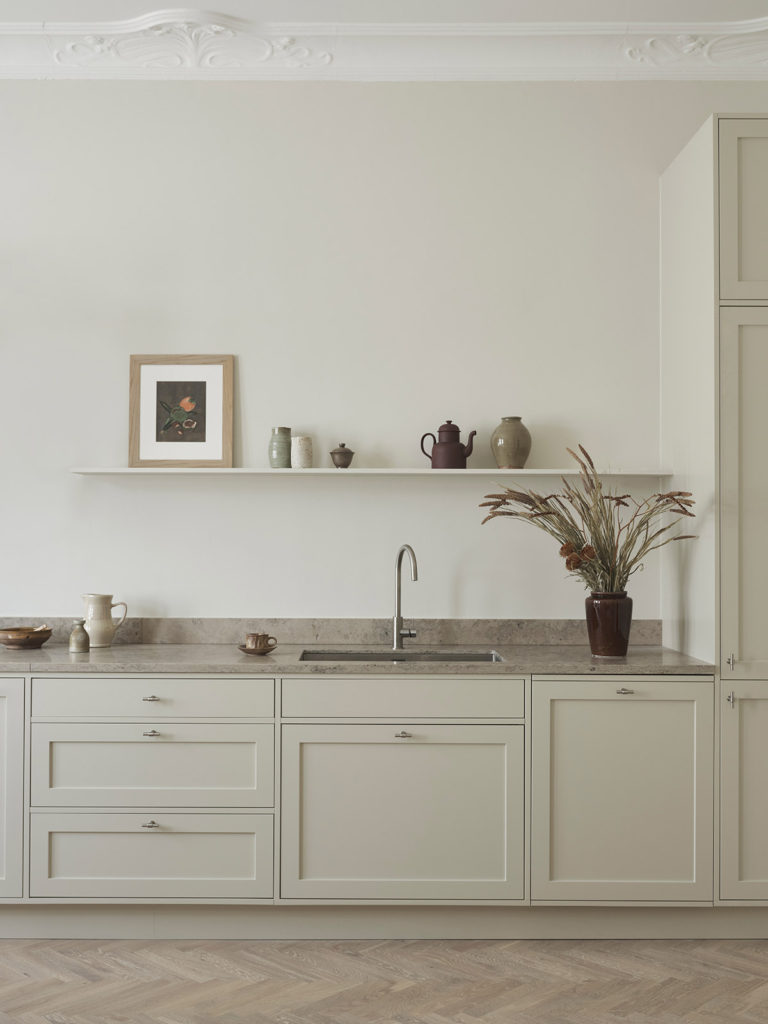 Off-white shaker kitchen, limestone countertop, hidden exhaust, stainless steel hardware, herringbone flooring