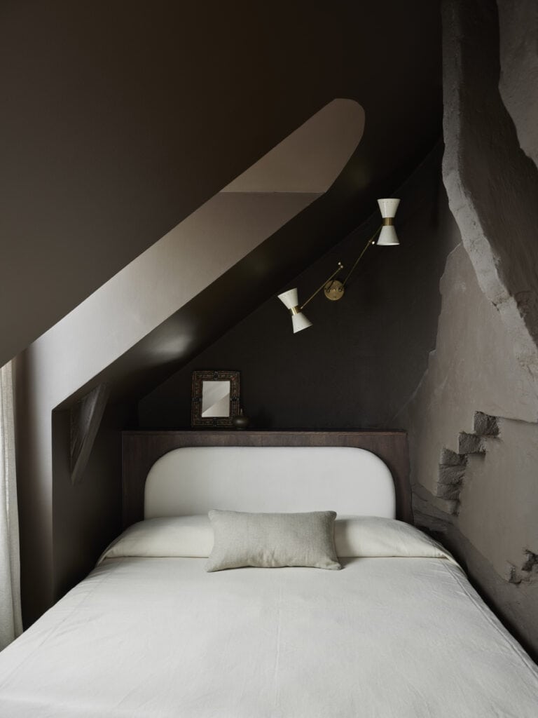 A tiny attic bedroom with dark brown walls