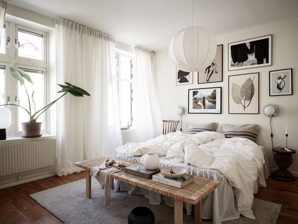 A white bedroom with a natural decor and a beautiful gallery wall above the bed