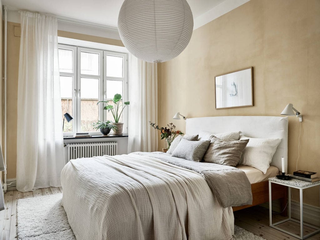 Beige walls with yellow undertones in a sunny bedroom. with white textiles