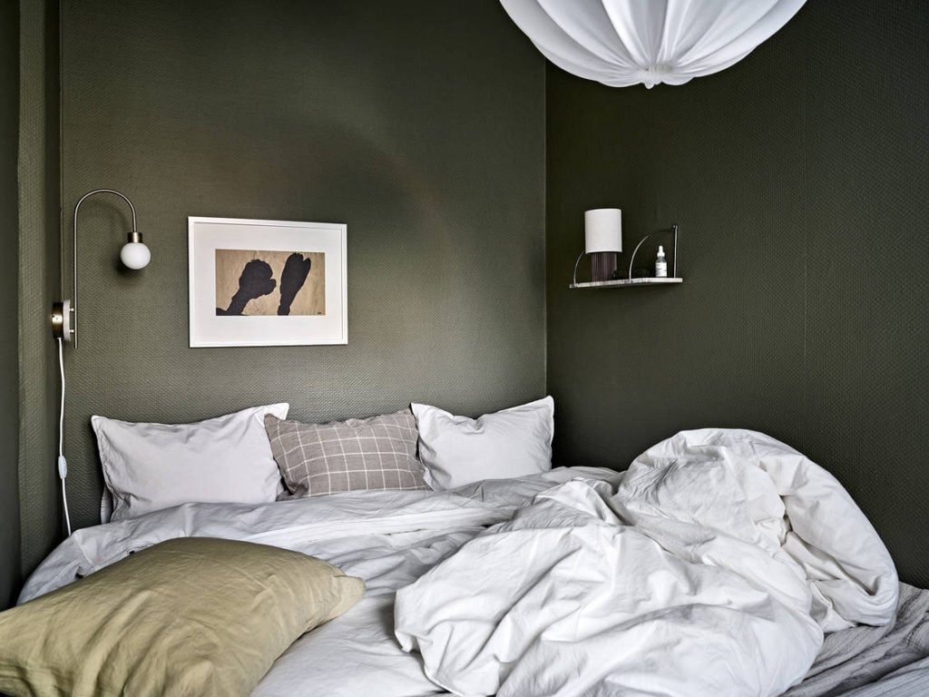 A small dark green bedroom with white bedding 