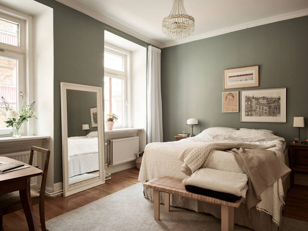 A dark green bedroom with a gallery wall in soft tones