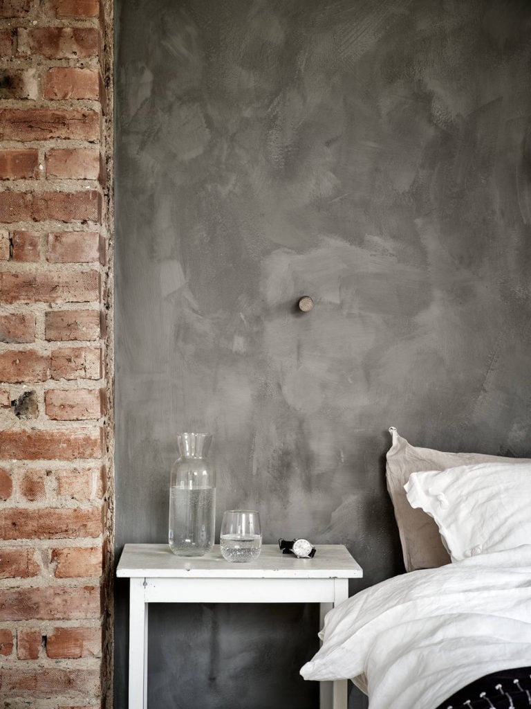 Exposed brick and grey limewash combined on a bedroom wall