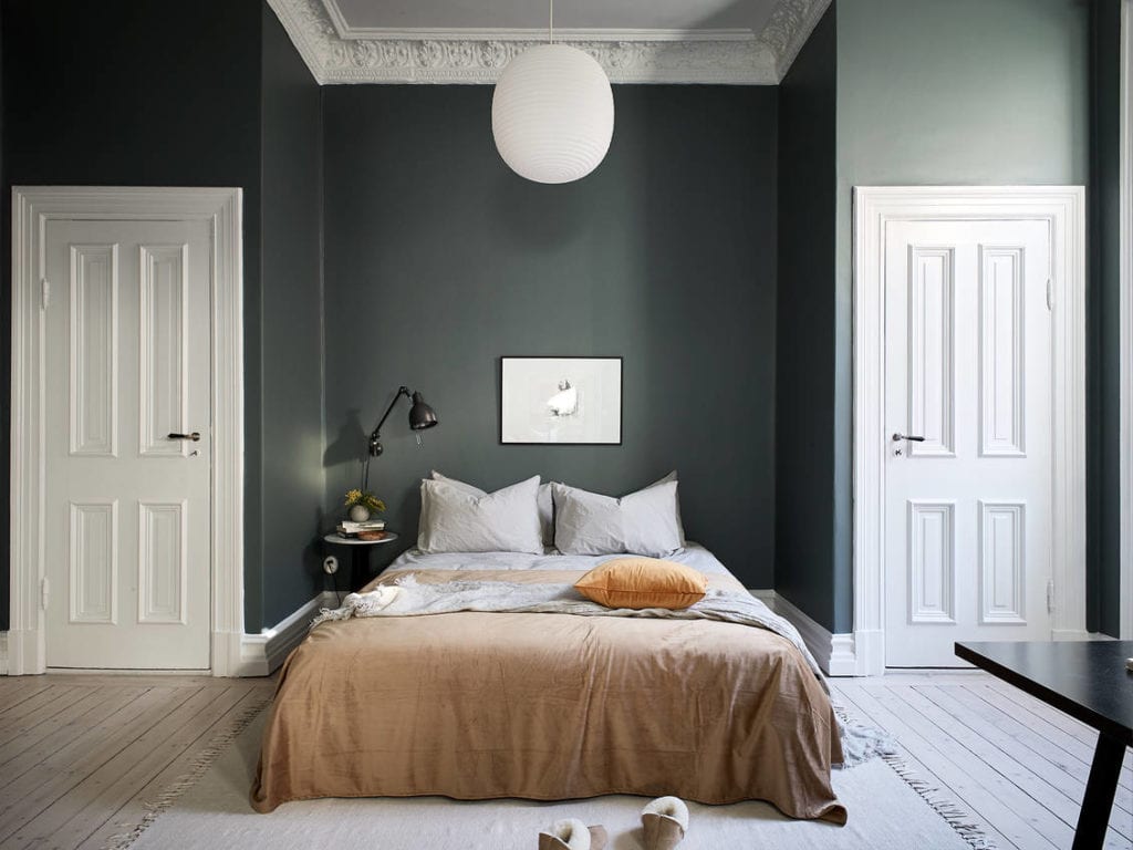 A dark green wall color in a historic bedroom with two walk-in closets next to the bed
